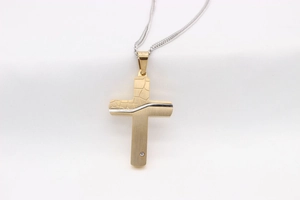 Detail of vintage gold cross pendant with rock texture and zircon stone on silver chain