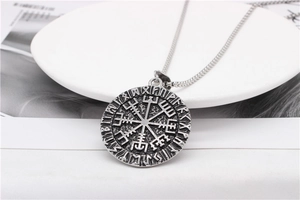 Macro shot of silver Viking Vegvisir compass pendant with engraved runes on metal disk