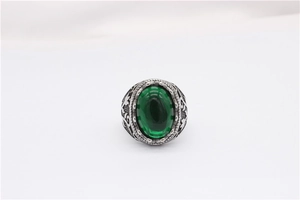 Vue détaillée d'une pierre ovale verte sertie dans une bague baroque en acier avec gravures