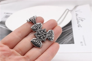 Macro shot of Viking Celtic knot pendant in vintage steel finish held by hand