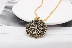 Macro detail of gold Viking Vegvisir compass pendant with engraved Nordic runes
