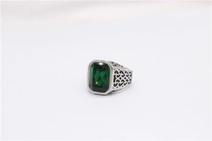 Macro shot of emerald cut green gemstone on engraved vintage steel signet ring