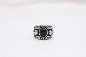 Macro detail of gothic skull ring featuring a large black gemstone and pave crystal accents