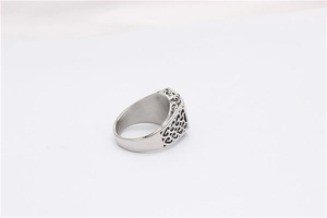 Detail of silver rectangle ring featuring intricate cutout geometric patterns on the side