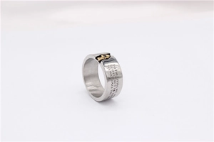 Detail of vintage steel ring showing brushed texture, gold skull, and engraved quote