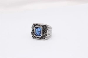 Gros plan sur une bague chevalière vintage avec pierre bleue et gravures de rinceaux