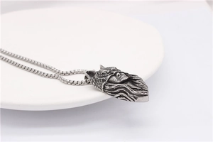Détail du pendentif tête de loup vintage avec relief mythique sur une chaîne à mailles