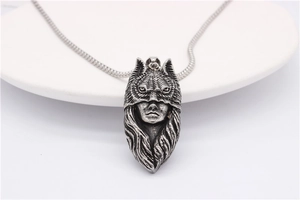 Détail du pendentif loup-garou rétro sur chaîne serpent posé sur un plateau en céramique