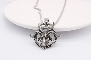 Detailed close-up of retro silver ram head pendant with pentagram symbol on white surface