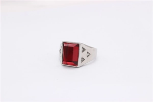 Gros plan sur une bague argentée avec zircon rouge rectangulaire et motifs triangles
