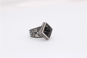 Close-up of vintage titanium steel ring with black bead and engraved floral patterns