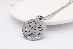 Gros plan d'un collier en acier argenté montrant un pendentif creux et une chaîne