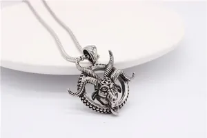 Detail of vintage silver ram head pendant with pentagram and serpent chain on ceramic