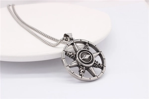 Detailed view of vintage steel compass pendant with realistic eye engraving on a tray