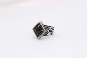 Close-up of vintage titanium steel ring with black gemstone and ethnic carvings