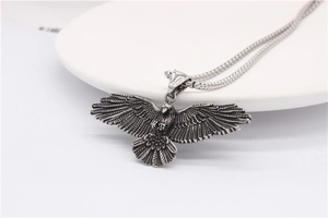 Vue détaillée du pendentif aigle avec finition argent vintage et textures de plumes