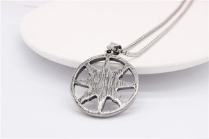 Detail of retro silver round pendant with brushed texture on white ceramic surface