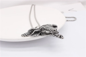 Detailed close-up of a vintage oxidised silver ram head pendant with gothic engravings