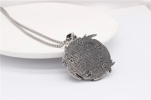 Close-up of vintage wolf head pendant with geometric symbols and antique steel finish