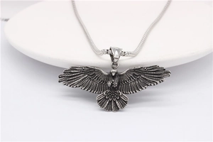 Gros plan détaillé d'un collier pendentif aigle vintage avec ailes texturées et chaîne fine