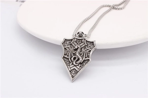 Macro view of vintage shield pendant featuring detailed embossed dragon totem in silver finish