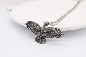 Gros plan du pendentif aigle argenté vintage avec ailes détaillées sur chaîne épaisse