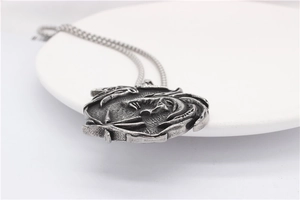 Macro shot of circular vintage silver dragon relief pendant with oxidized metal texture