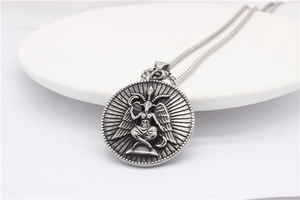 Detailed close-up of retro silver Baphomet pendant necklace on white ceramic