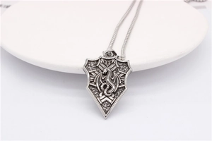 Detailed close-up of retro dragon totem shield pendant with oxidized steel texture