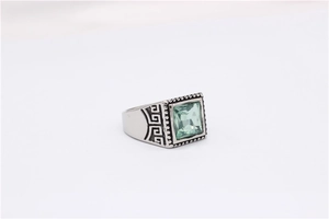 Macro shot of silver titanium steel ring with green gemstone and Greek Key pattern