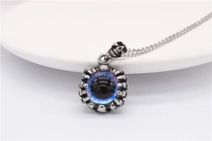 Macro shot of gothic evil eye pendant with skull and metallic claws on silver chain