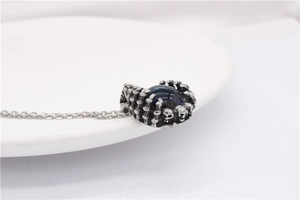 Macro shot of gothic skeleton claw pendant with deep blue gemstone on stainless steel chain