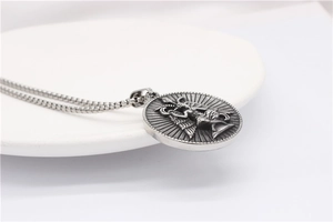 Close-up of vintage silver necklace showing embossed winged angel pendant and steel chain