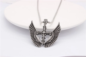 Macro view of vintage stainless steel cross pendant with detailed wing textures