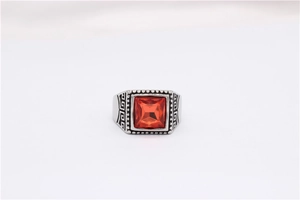 Macro detail of men's vintage steel ring featuring square red stone and Greek key pattern