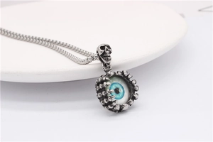 Detail of gothic skull pendant with skeletal hand clutching a realistic blue eye