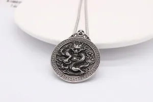 Detail shot of antique silver dragon pendant with intricate relief and greek fret border