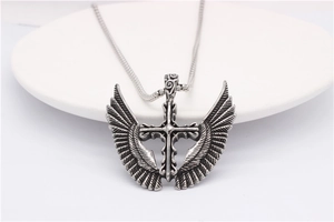 Detailed view of vintage silver winged cross pendant with intricate feather textures