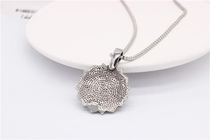 Detail showing the textured honeycomb pattern on the back of a silver lotus pendant