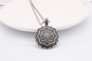 Detailed macro of vintage silver lotus mandala pendant with Om symbol on white plate