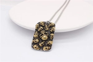 Détail du pendentif plaque militaire rétro avec crânes dorés sur acier titane texturé noir