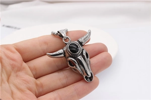 Close-up of vintage bull skull pendant with black gemstone on a steel ball chain