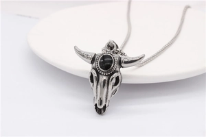 Macro detail of a vintage ram skull pendant with a black gem on a stainless steel chain