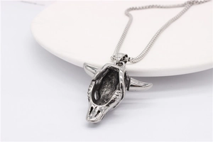 Detailed view of punk style ram skull pendant in vintage silver finish on white ceramic