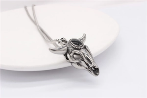 Detail of vintage bull skull pendant featuring a black oval gemstone inlay with aged finish