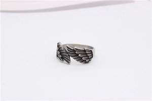 Close-up of vintage steel ring featuring detailed feather textures and silver wings