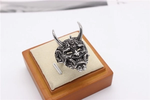 Macro shot of retro silver Hannya mask ring with detailed horns on beige velvet jewelry stand