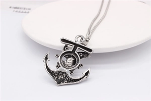 Detail of vintage punk anchor and helm pendant with antique silver finish on white stand