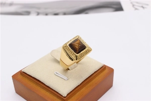 Detailed macro view of gold signet ring with tiger eye stone and Greek key patterns