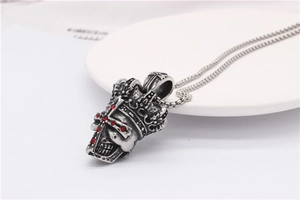 Détail du pendentif crâne argenté vintage avec couronne et cristaux rouges